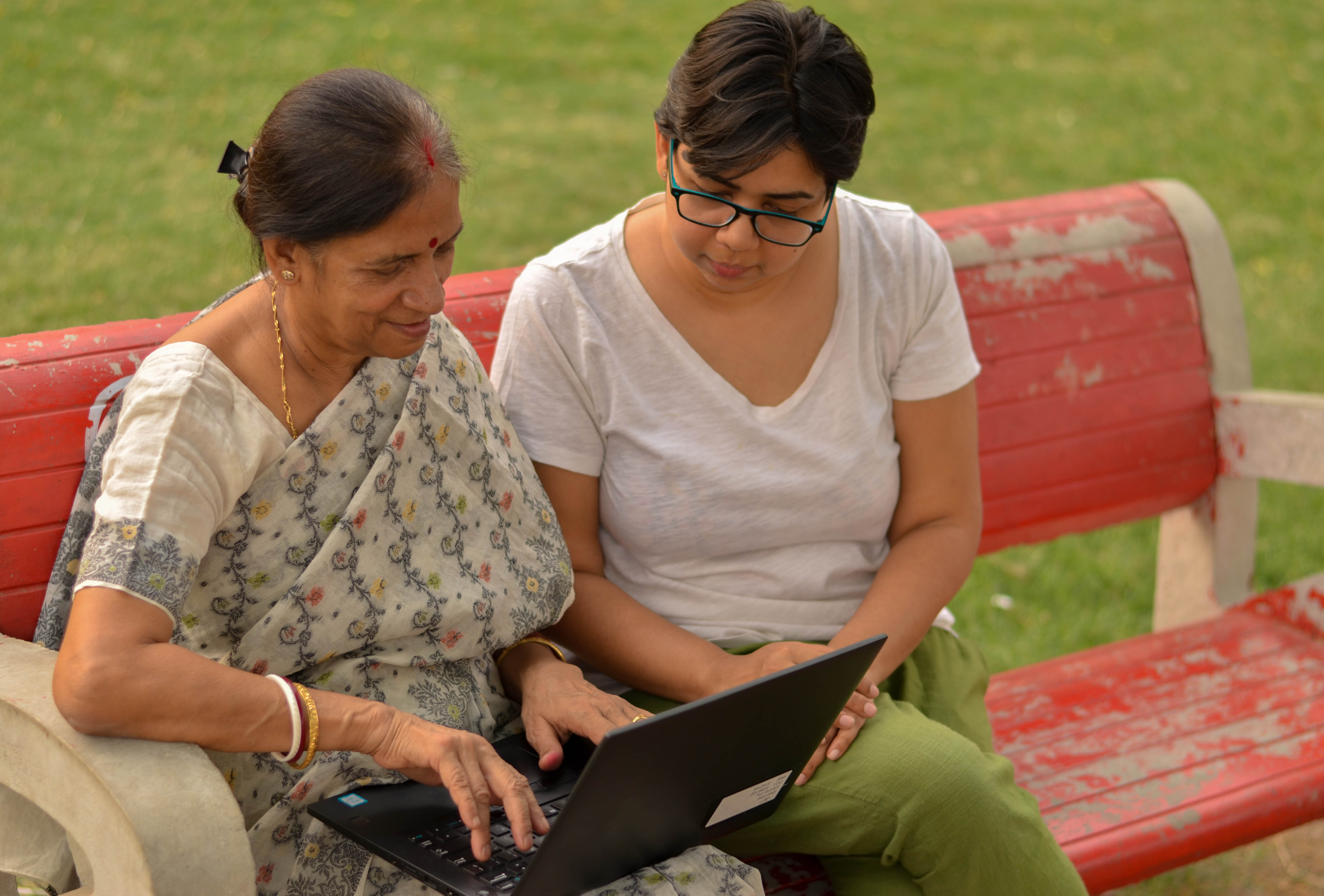 Young Indian girl helping an old Indian woman on a laptop 